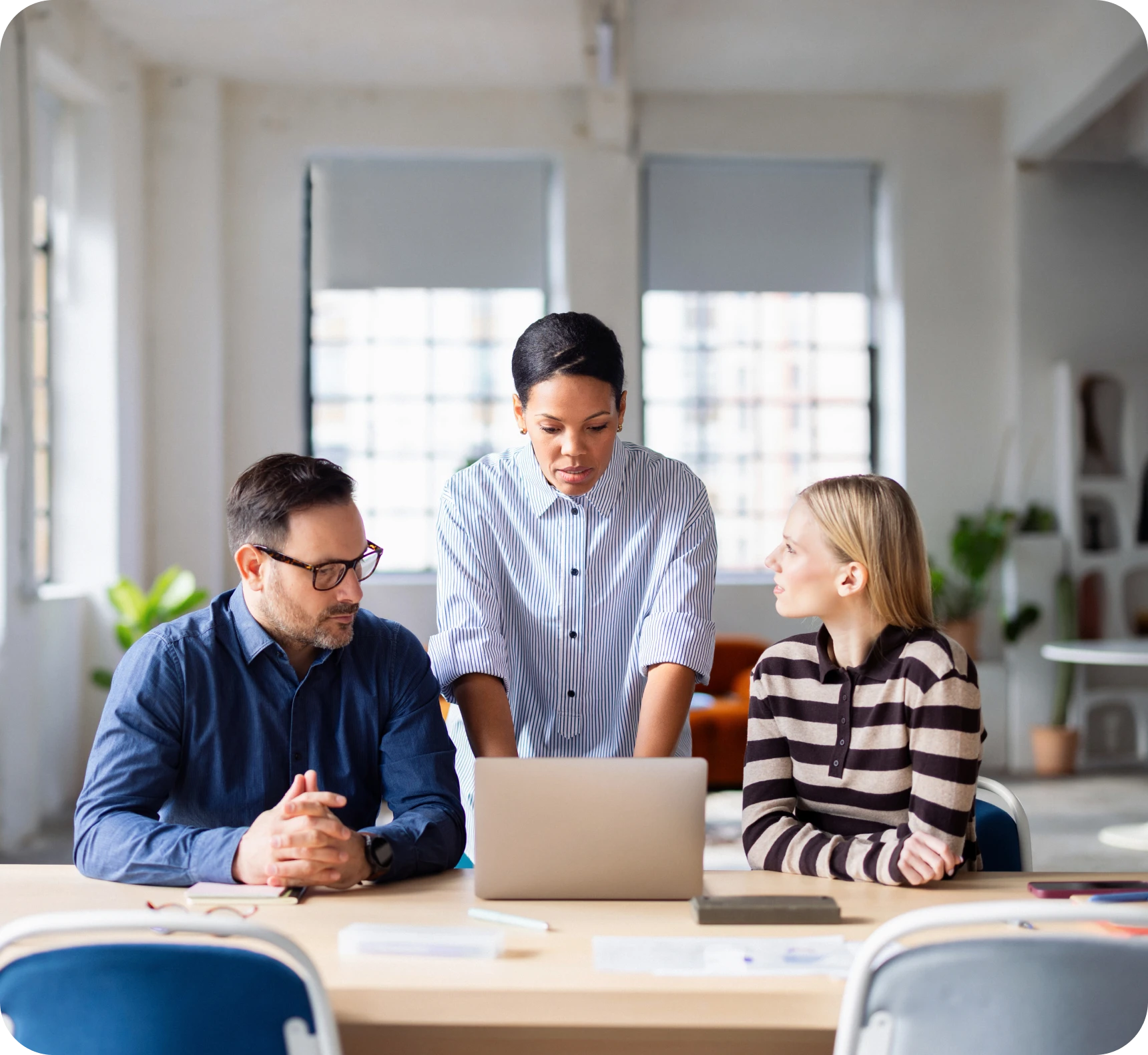 Three colleagues discussing work at desk